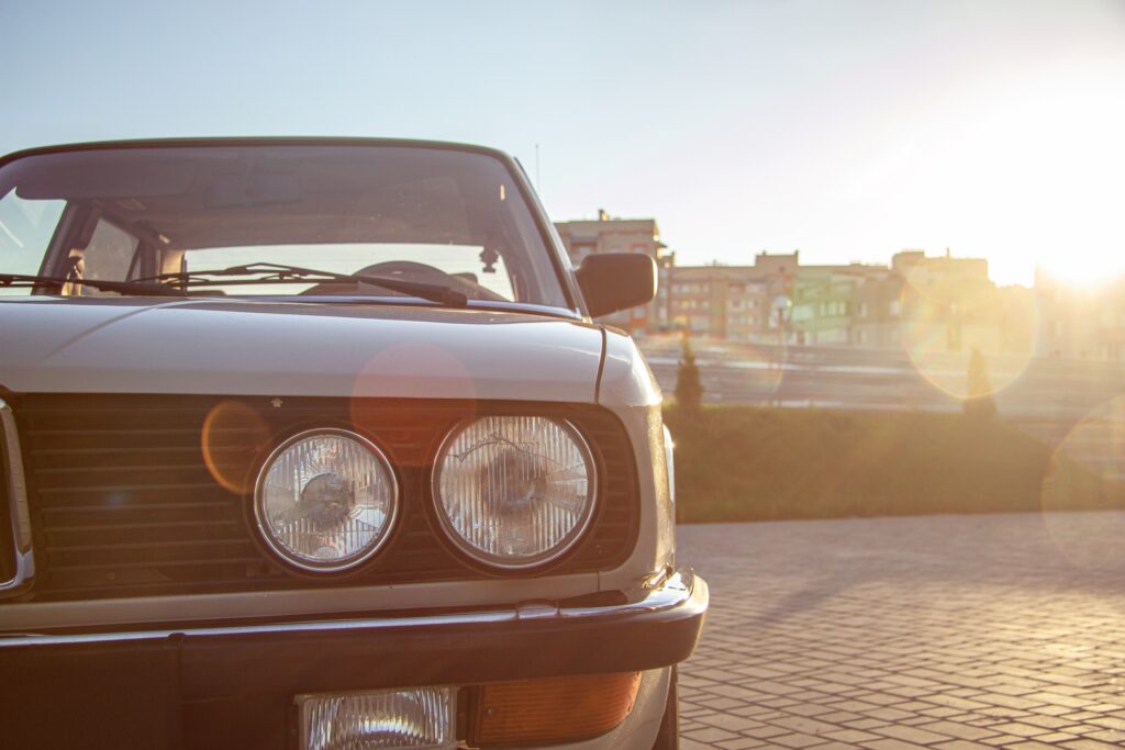 The closeup shot of the round headlight of a white vintage classic car during sunset